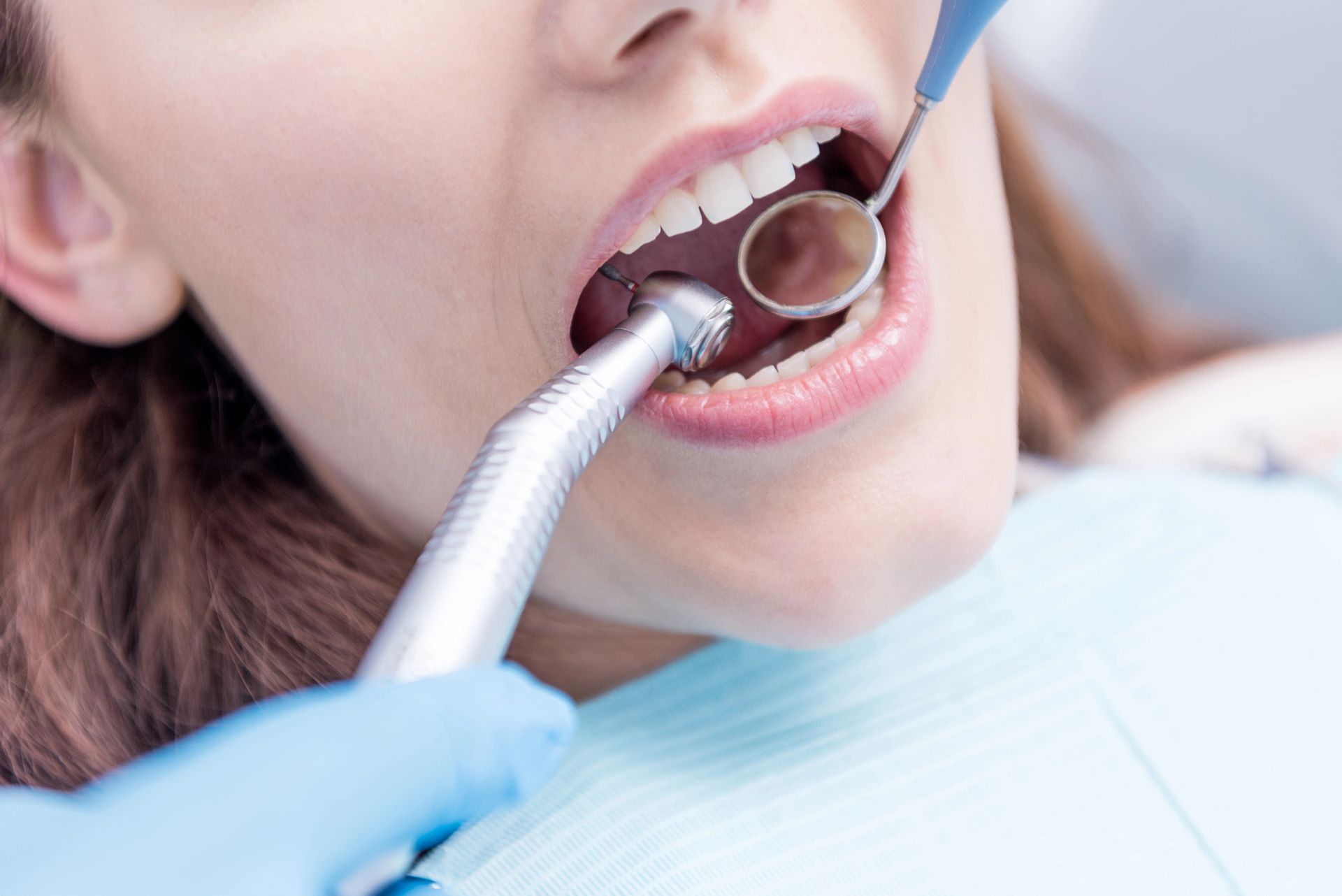 Dentista che utilizza uno strumento durante una visita odontoiatrica a bocca aperta su un paziente.