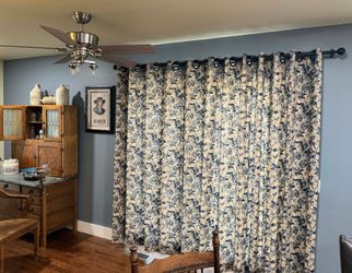 A living room with blue and white curtains and a ceiling fan