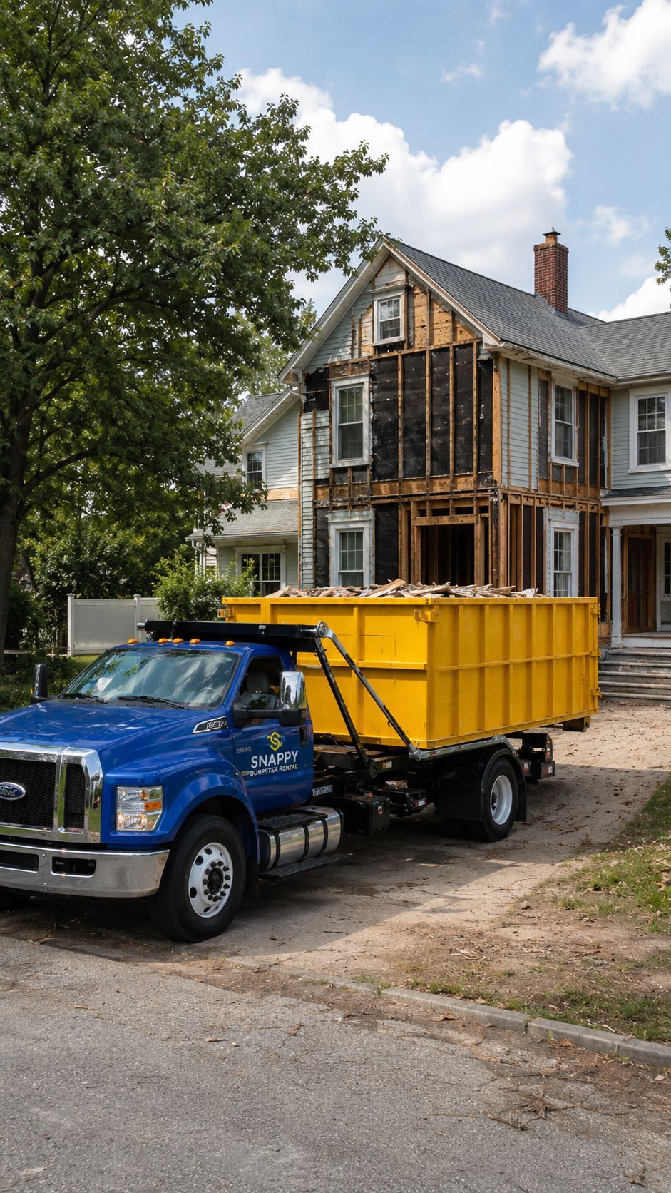 Blue Snappy Dumpster Rental truck picking up a dumpster in front of a home renovation project