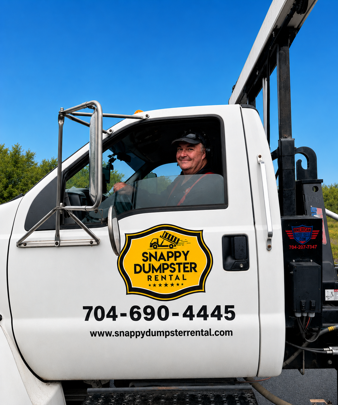 Snappy Dumpster Rental driver Mike Little smiling from the window of a Snappy Dumpster Rental branded roll-off dumpster truck