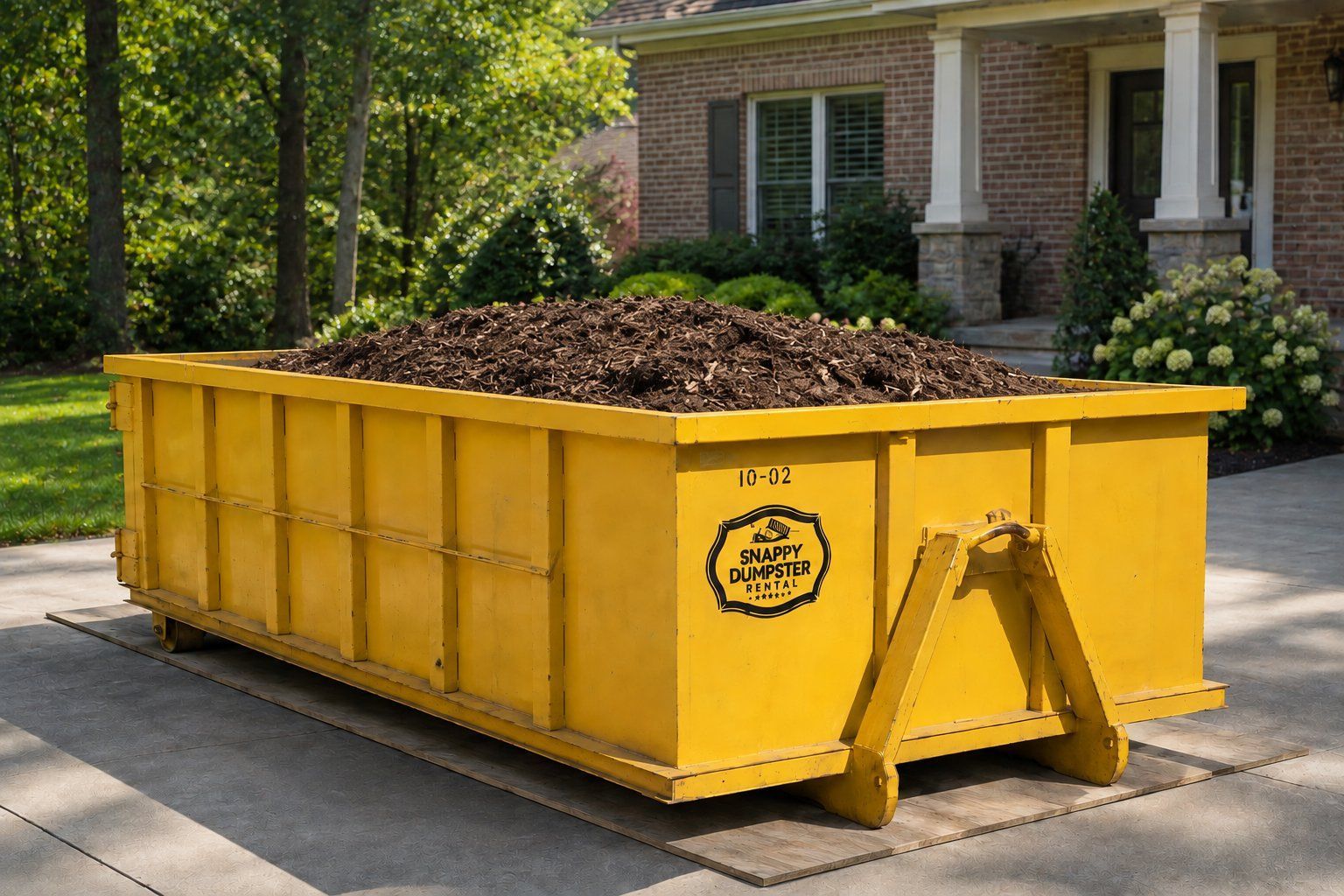 Snappy Dumpster Rental roll-off container filled with mulch, left on plywood on a residential driveway in Charlotte NC