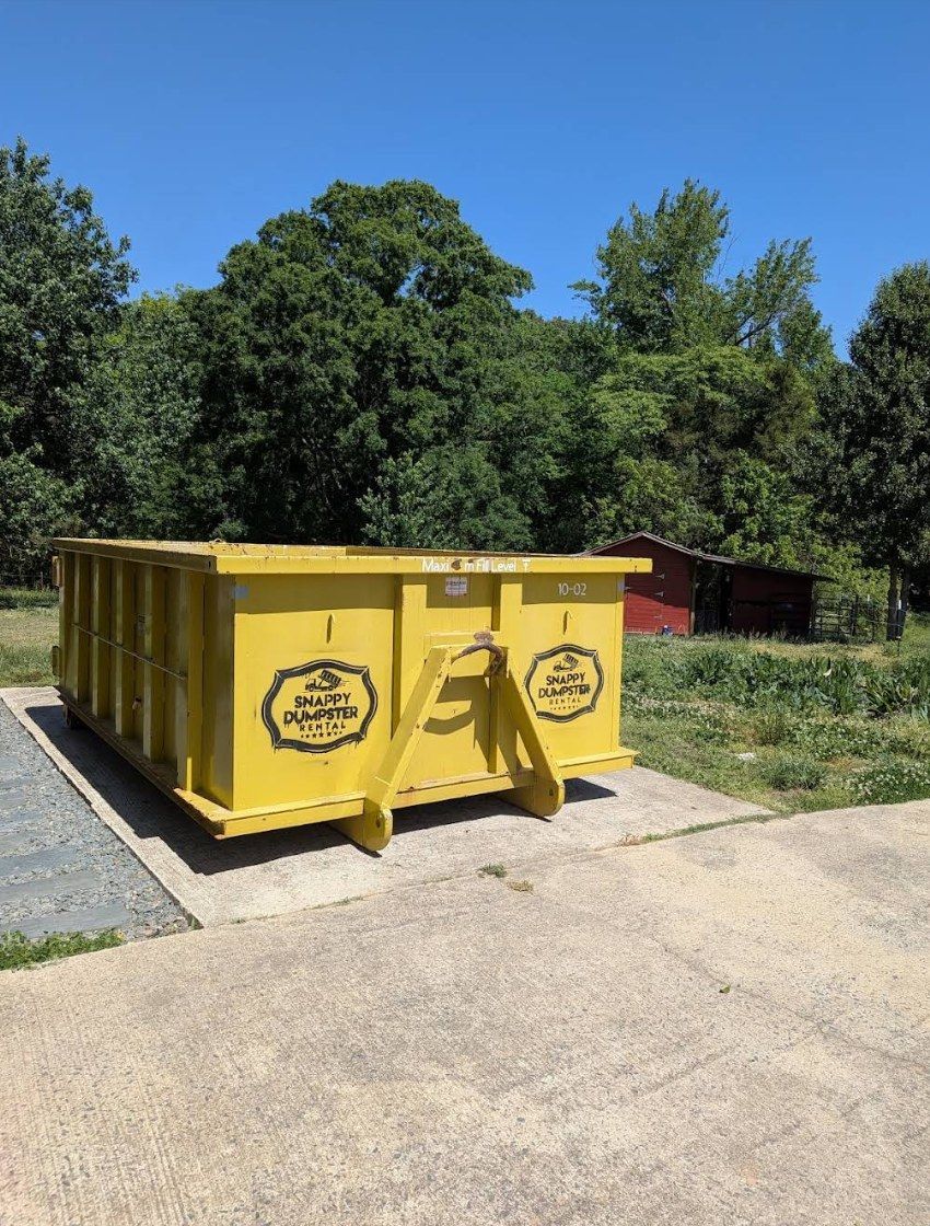 Snappy 10-yard dumpster, unit 10-02, on a concrete pad at a rural property in Monroe, NC