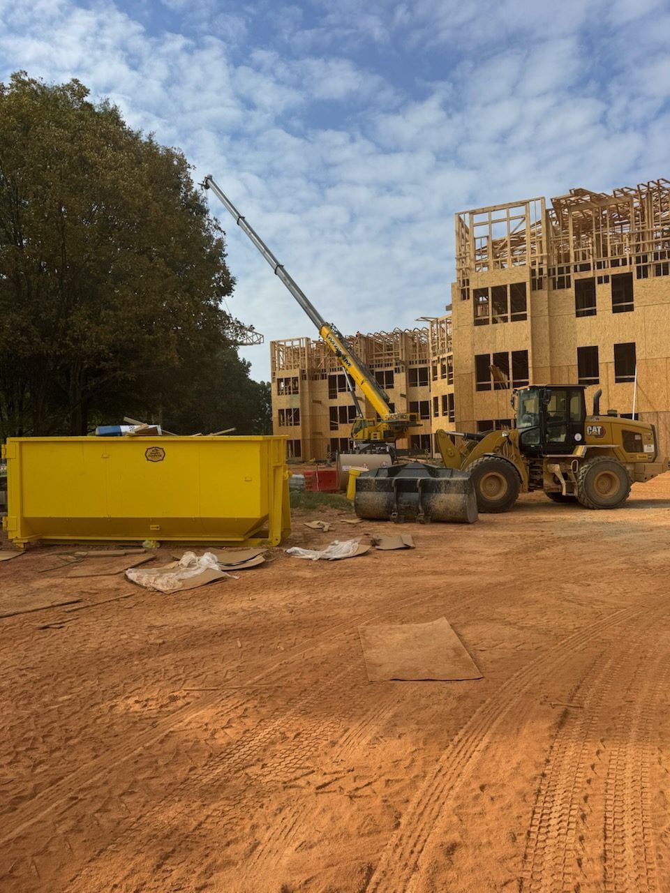 Snappy 30-yard dumpster near a crane and loader on an apartment construction site