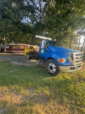 Snappy blue Ford F650 roll-off truck delivering a 15-yard dumpster for a rental move-out cleanout in Monroe, NC