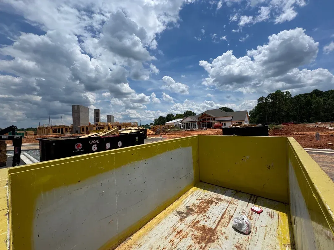 Yellow metal skip bin at a construction site under a cloudy sky