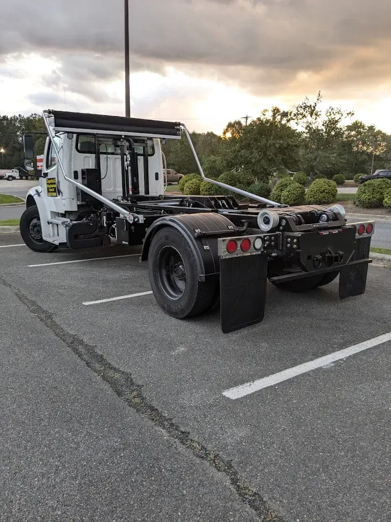 White tow truck chassis parked in a lot at dusk, viewed from the rear side.