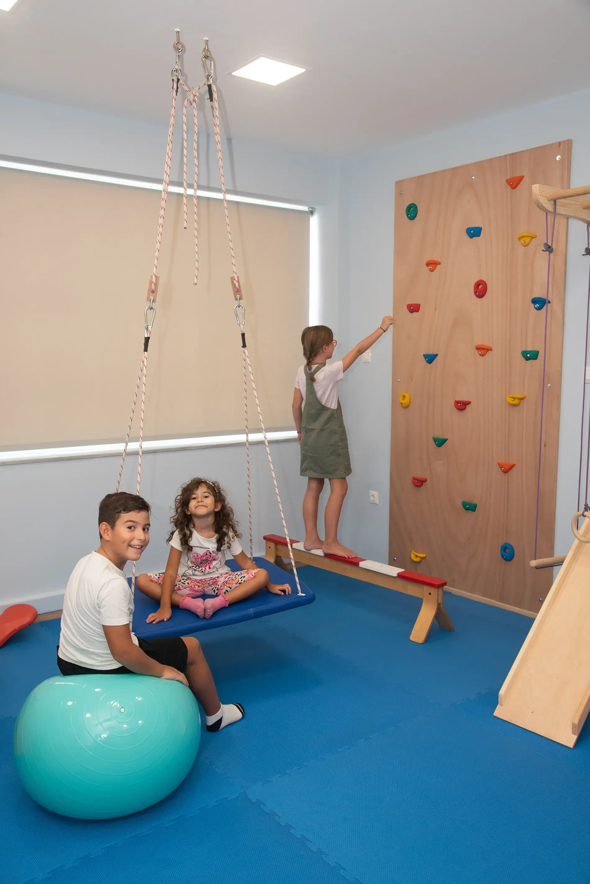 Μια ομάδα παιδιών παίζουν σε ένα δωμάτιο με έναν τοίχο αναρρίχησης.