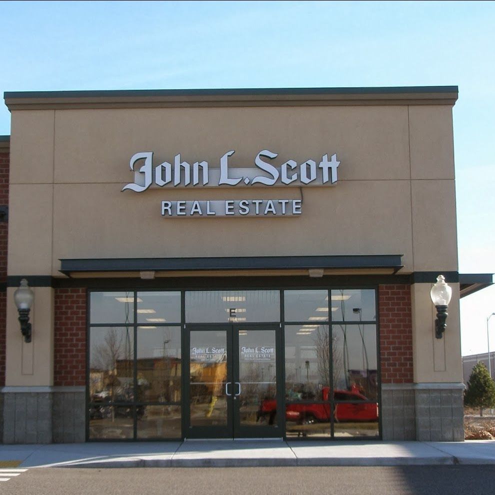 The front of a building with a green awning and a sign that says john l. scott real estate.