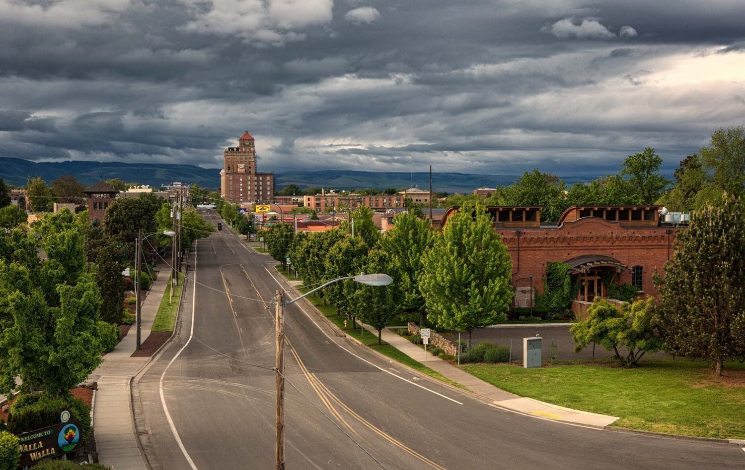 An aerial view of a city street with a cloudy sky in the background.