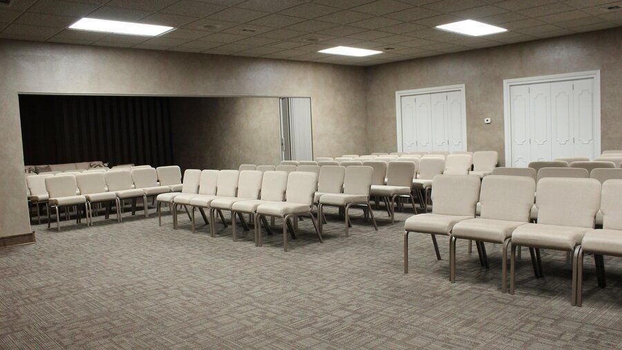 Service hall with rows of cream chairs at Campbell-Aman Funeral Home.