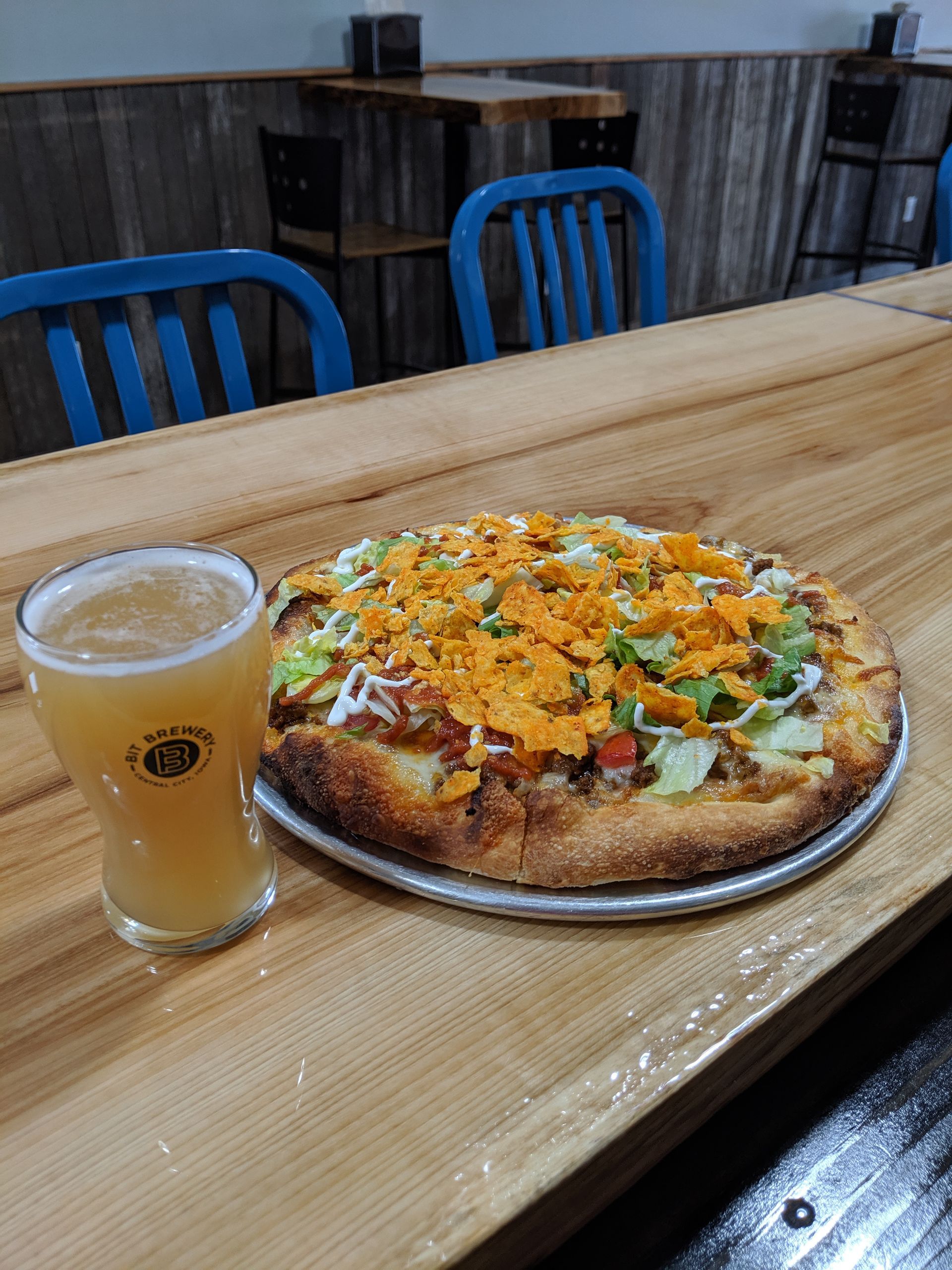 Taco pizza next to a wheat beer.