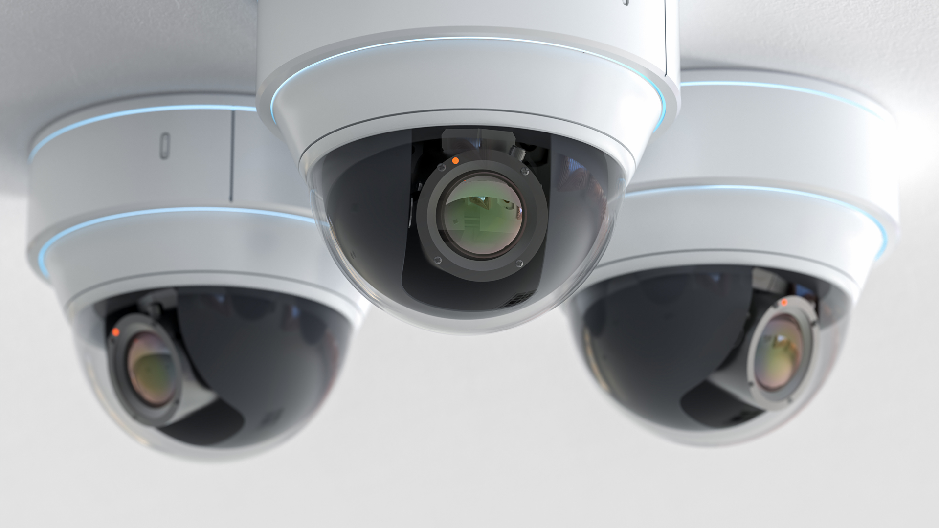 Technician installing a white security camera with a wrench indoors
