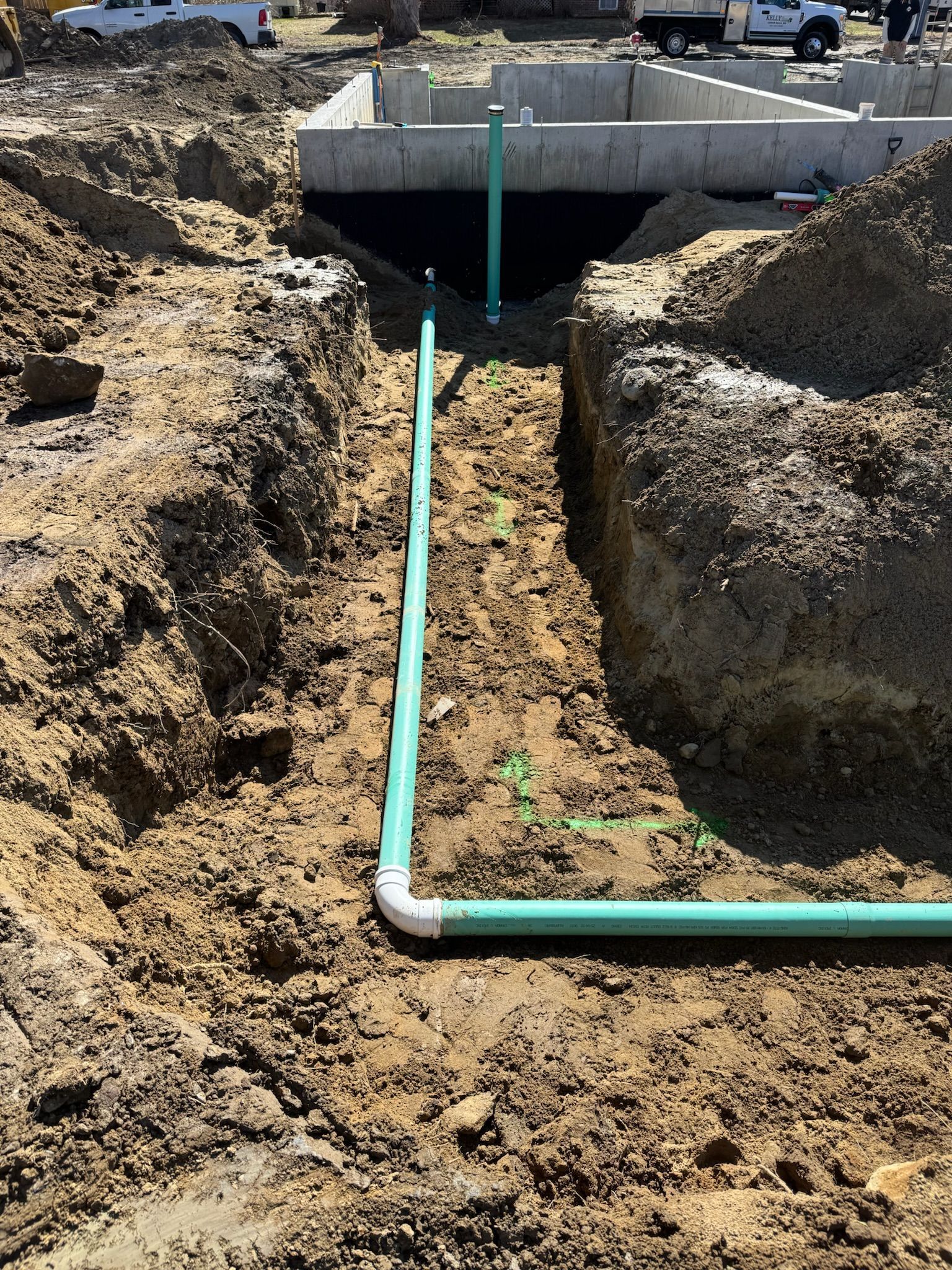 Trench with white pipe under a concrete slab at a construction site