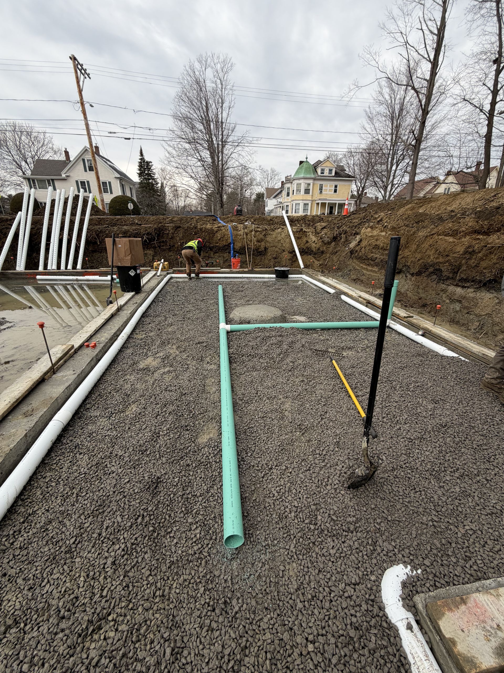 Backyard gravel patio with turquoise frame, black poles, and leafless trees under cloudy sky
