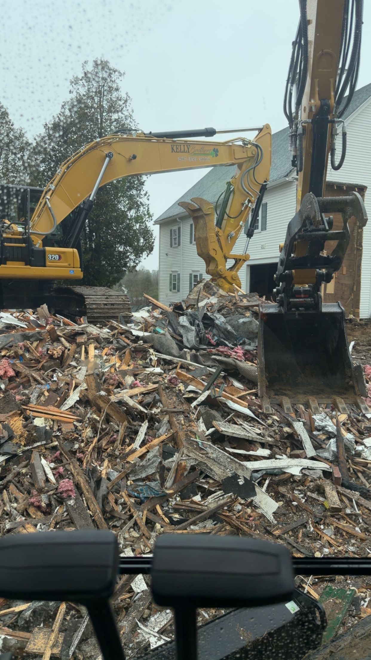 Excavators working in a demolition site with a large pile of debris and rubble.