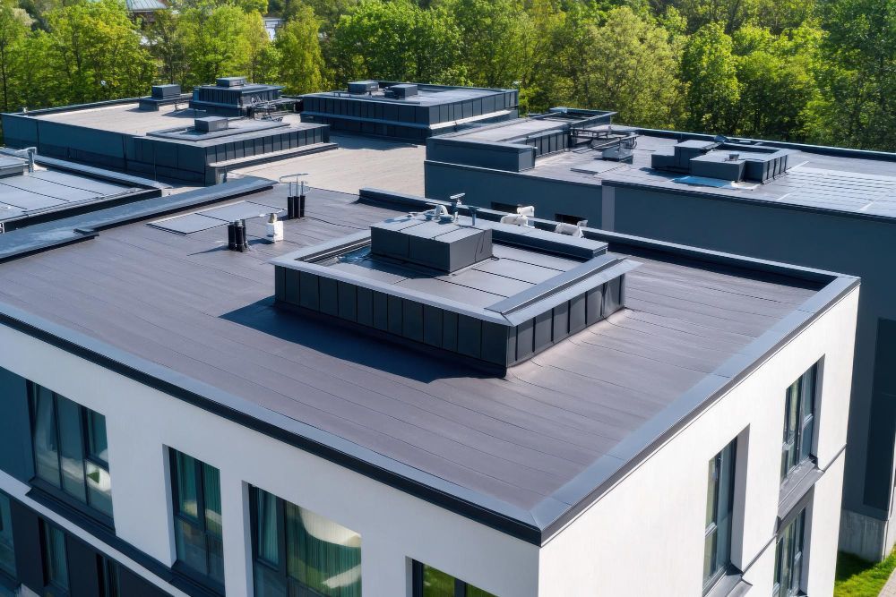 Modern flat-roof apartment building with rooftop vents and surrounding trees