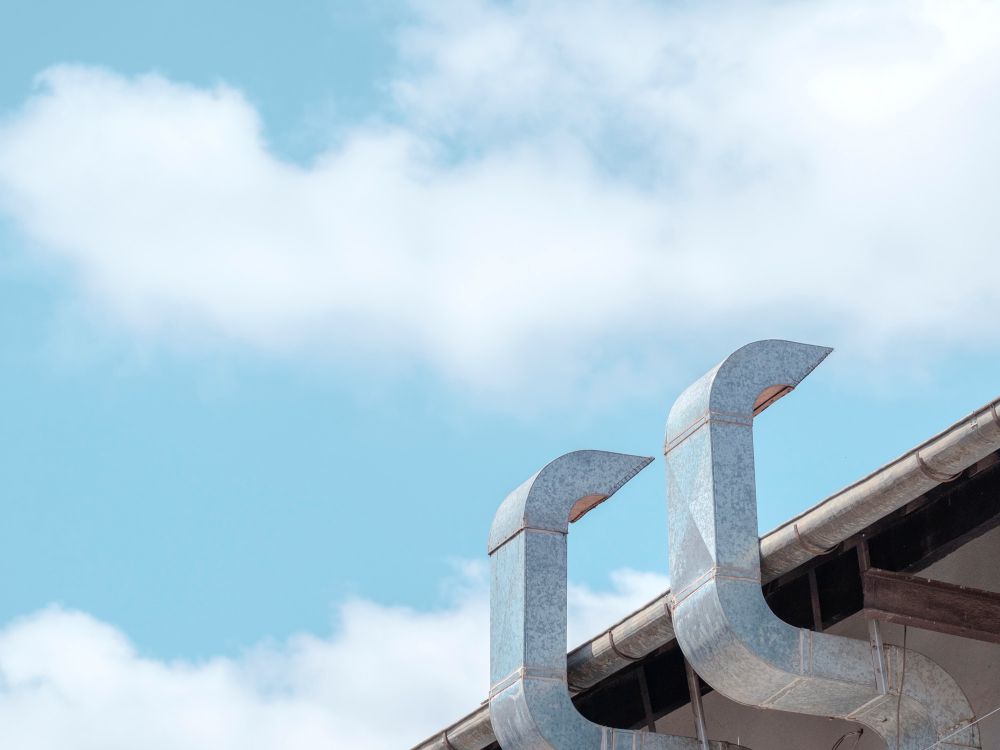 Metal rooftop vents against a blue sky with white clouds