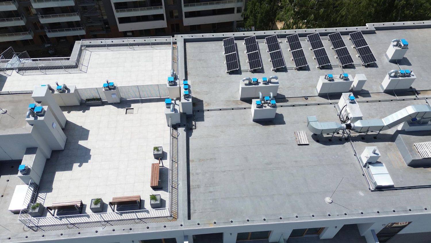 Rooftop with white HVAC units and vents on a gray commercial building, viewed from above
