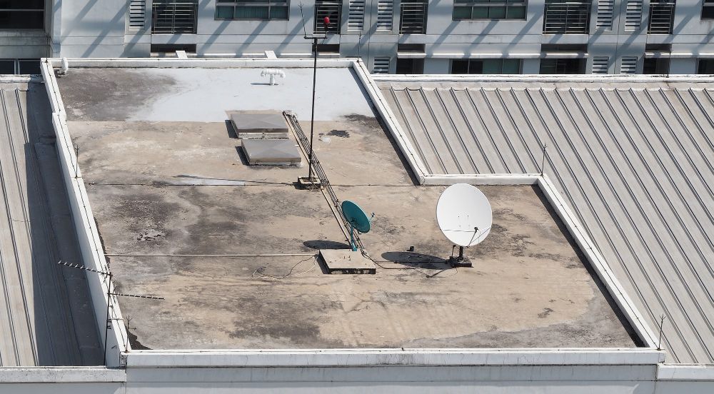 Rooftop with two satellite dishes and rooftop equipment on a flat, weathered surface