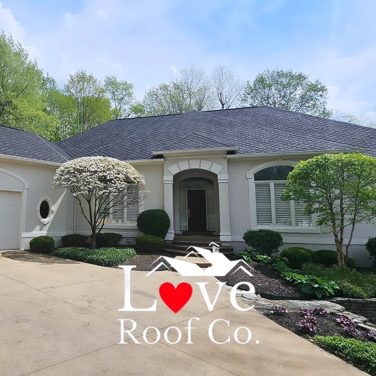 Single-story white house with dark roof, manicured landscaping, and Love Roof Co. watermark.