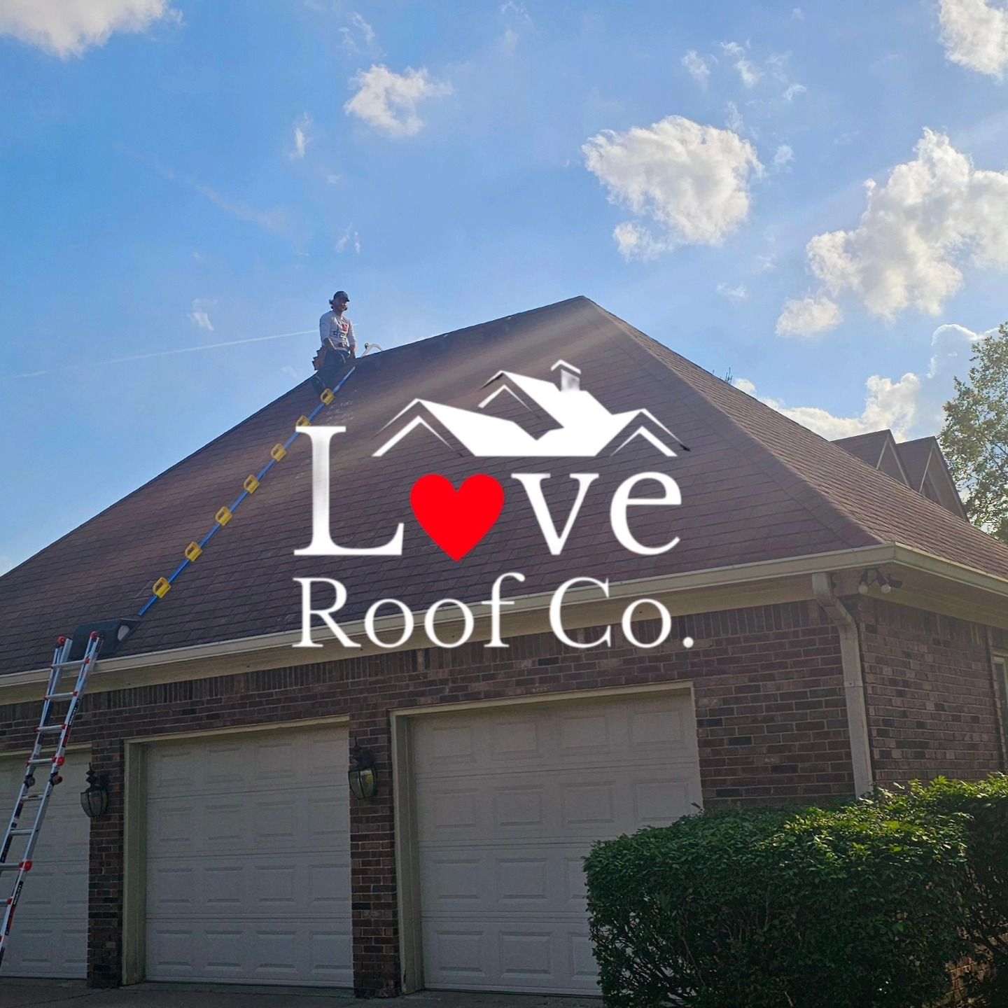 Worker on a ladder on a brick house roof beside a Love Roof Co. logo under a blue sky