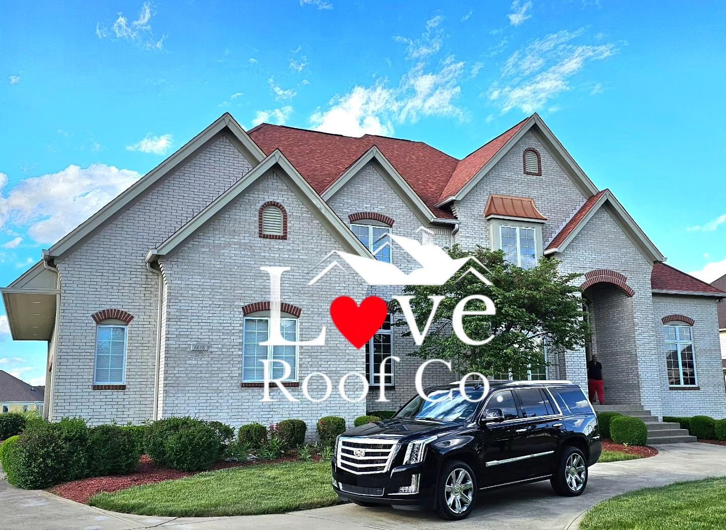 Love Roof Co. branding over a large gray house with red roof and black SUV in front