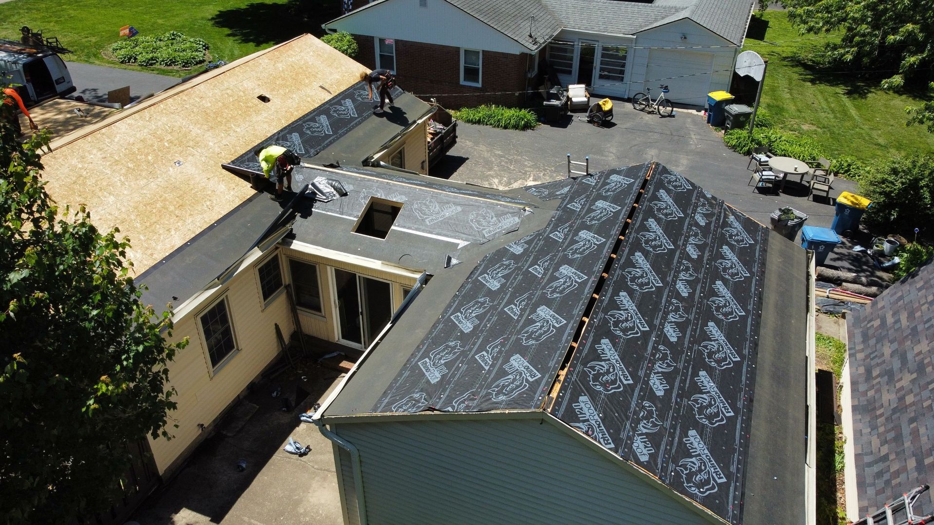 Aerial view of a house undergoing roof replacement after storm damage