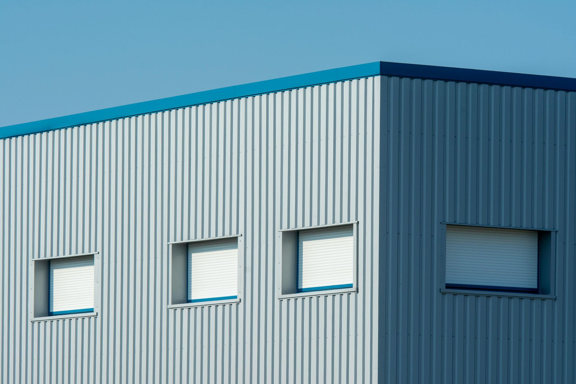 Modern industrial building facade with blue corrugated metal siding and small windows
