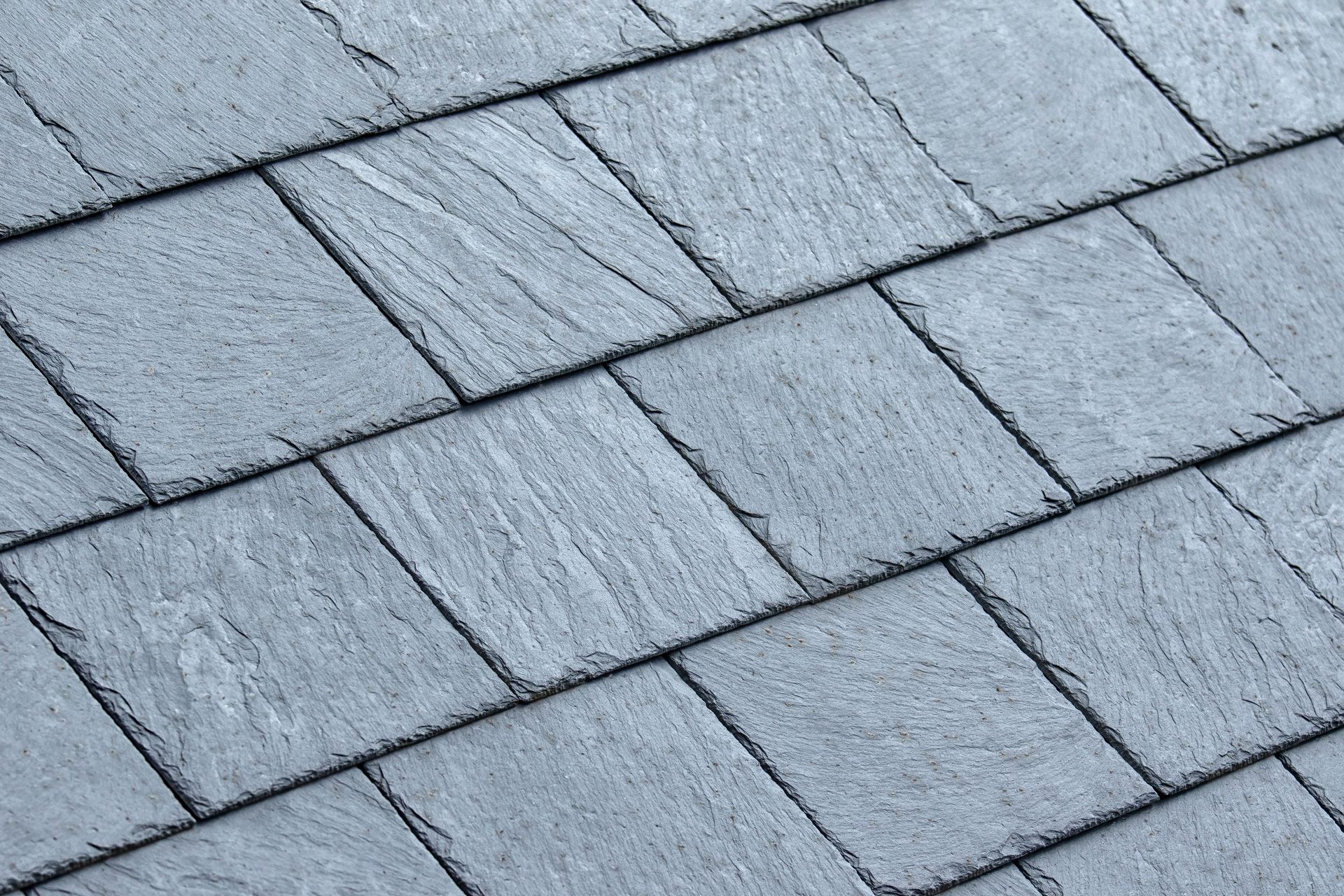 Close-up of gray slate roof shingles with a textured, overlapping pattern