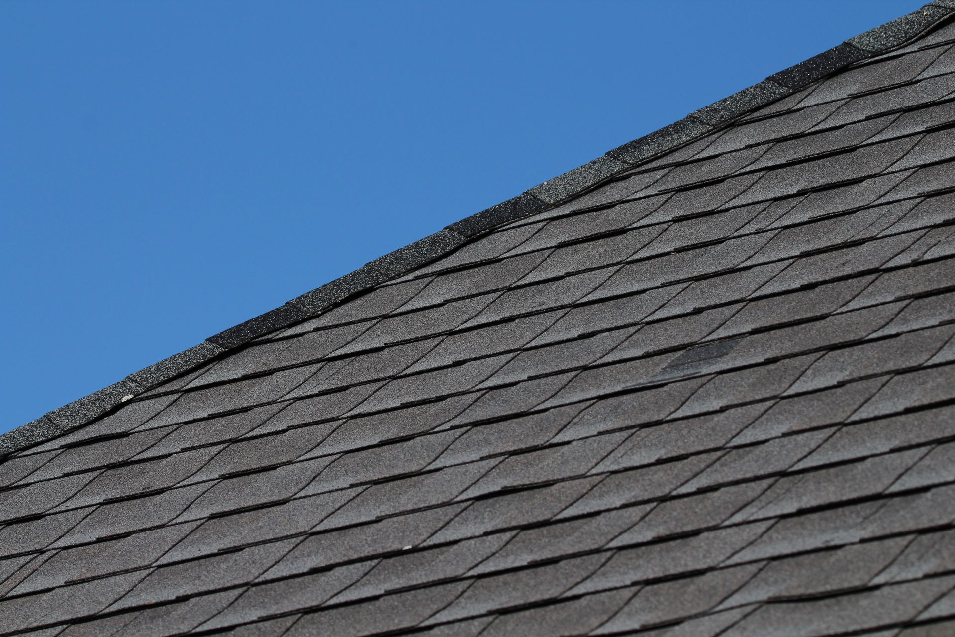 Gray shingled roof against a clear blue sky