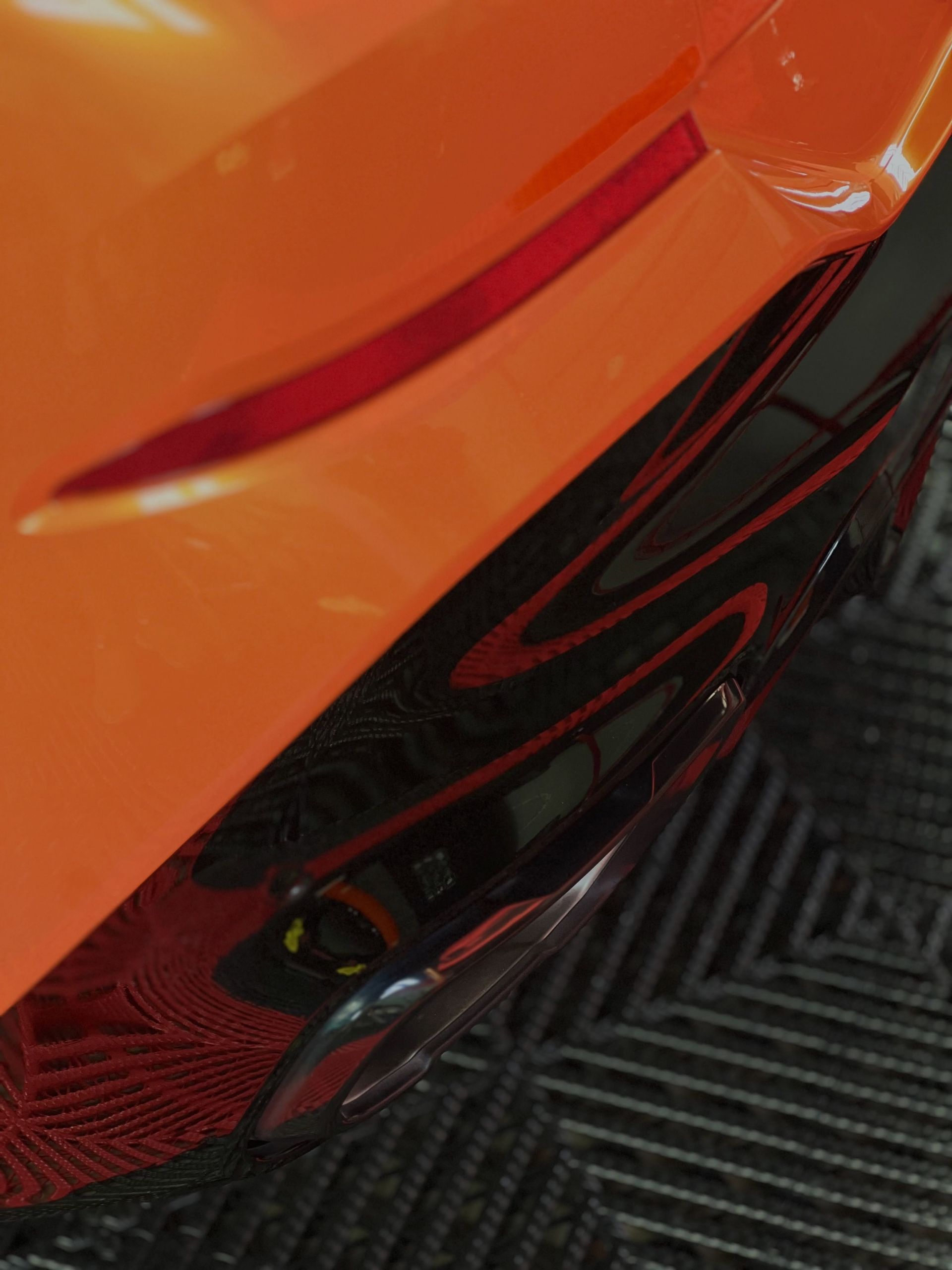 Close-up of orange and black car bodywork with glossy red trim