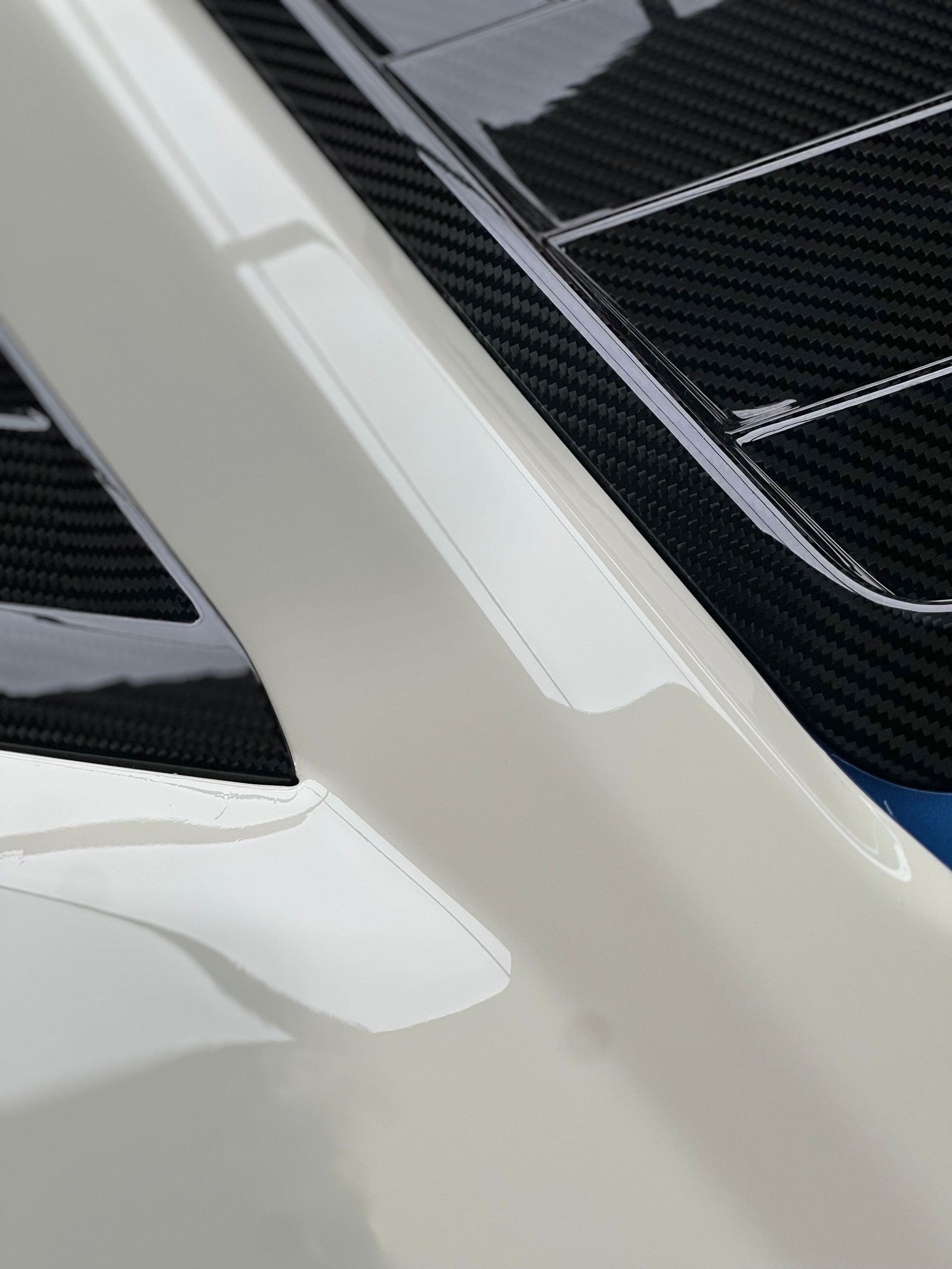 Close-up of a white car’s rear window and body panel with black trim.