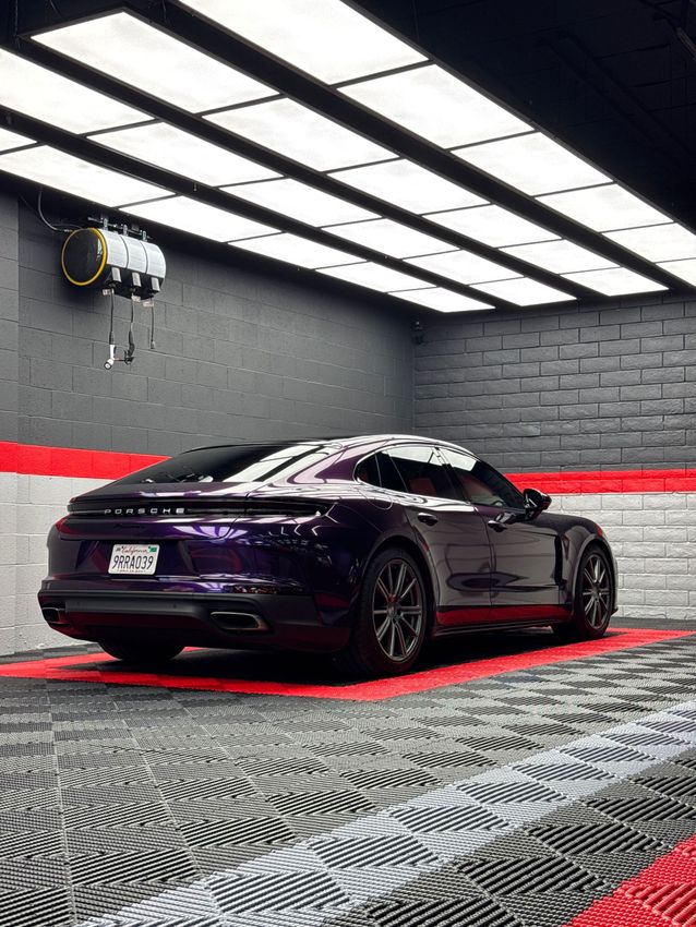 Black sports car in a sleek garage with red accent lighting and patterned floor tiles