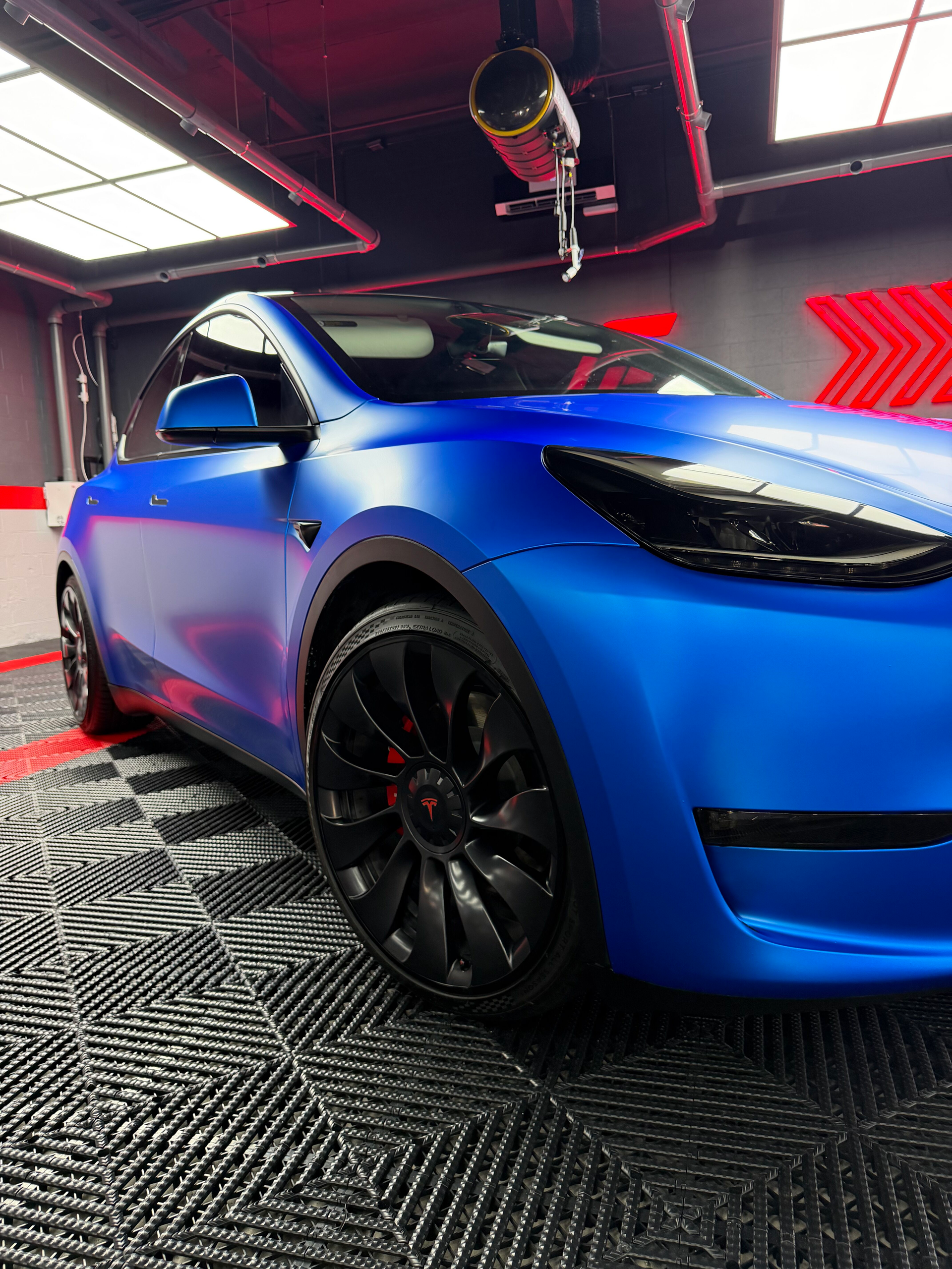 Black sports car in a sleek garage with red accent lighting and patterned floor tiles