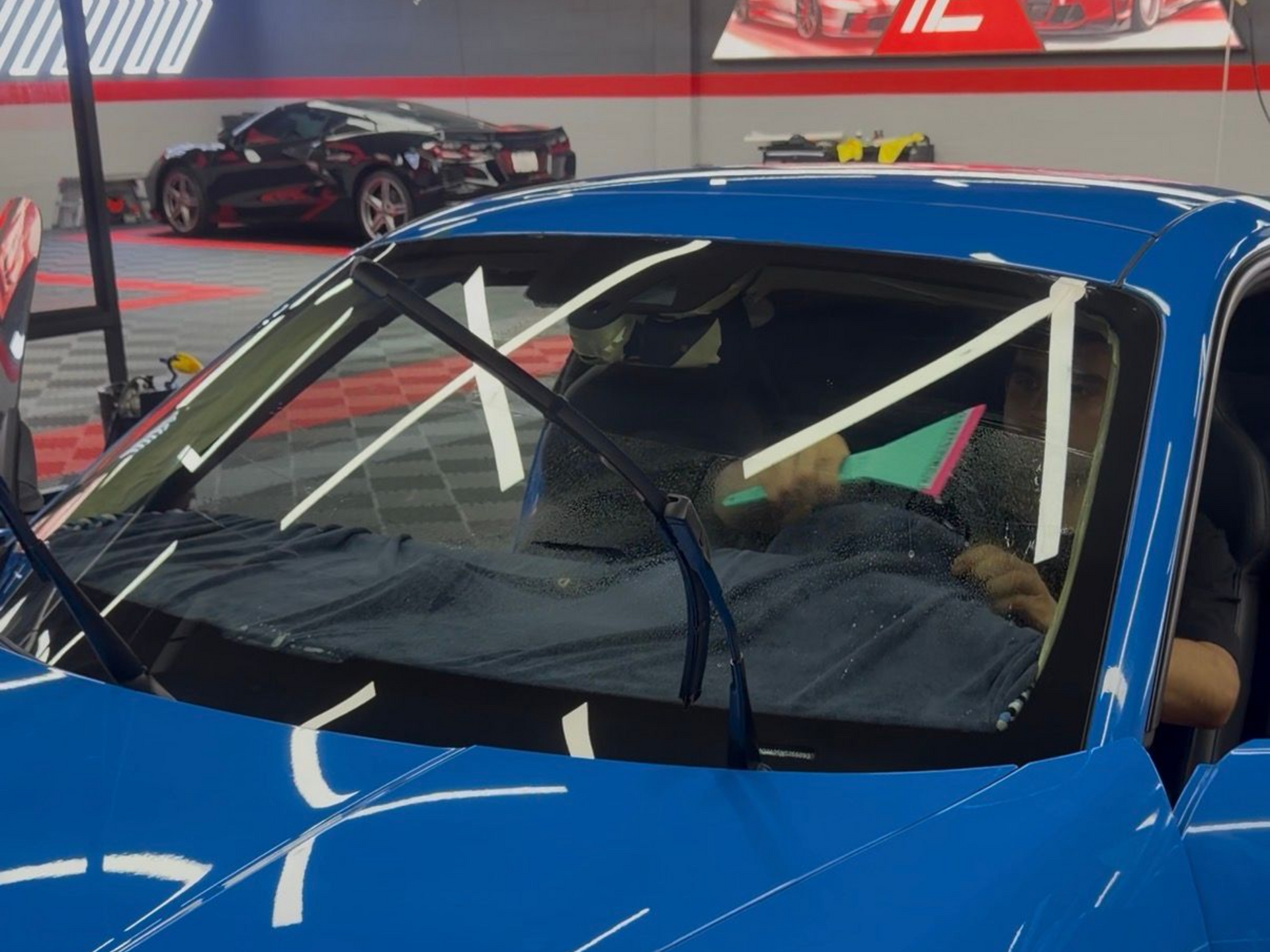 Person using a drill to repair a car windshield in a garage