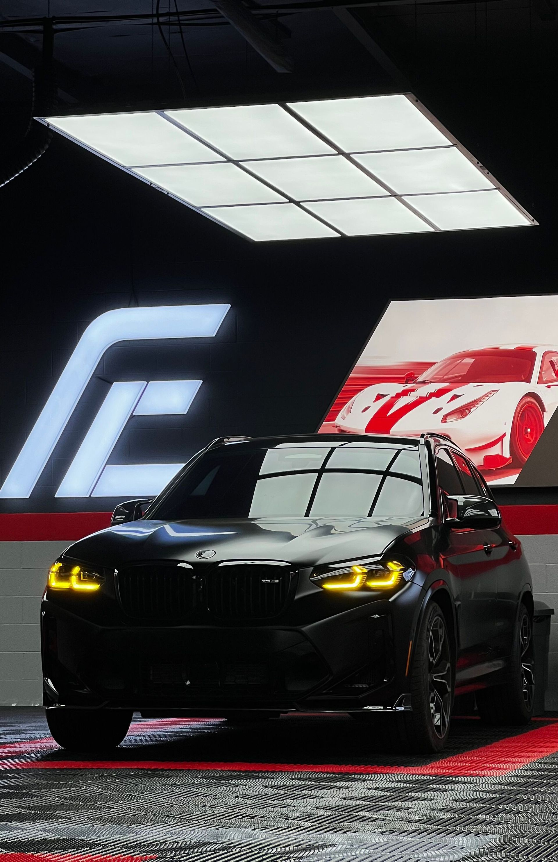 Black BMW SUV with yellow headlights in a glossy showroom under bright ceiling lights