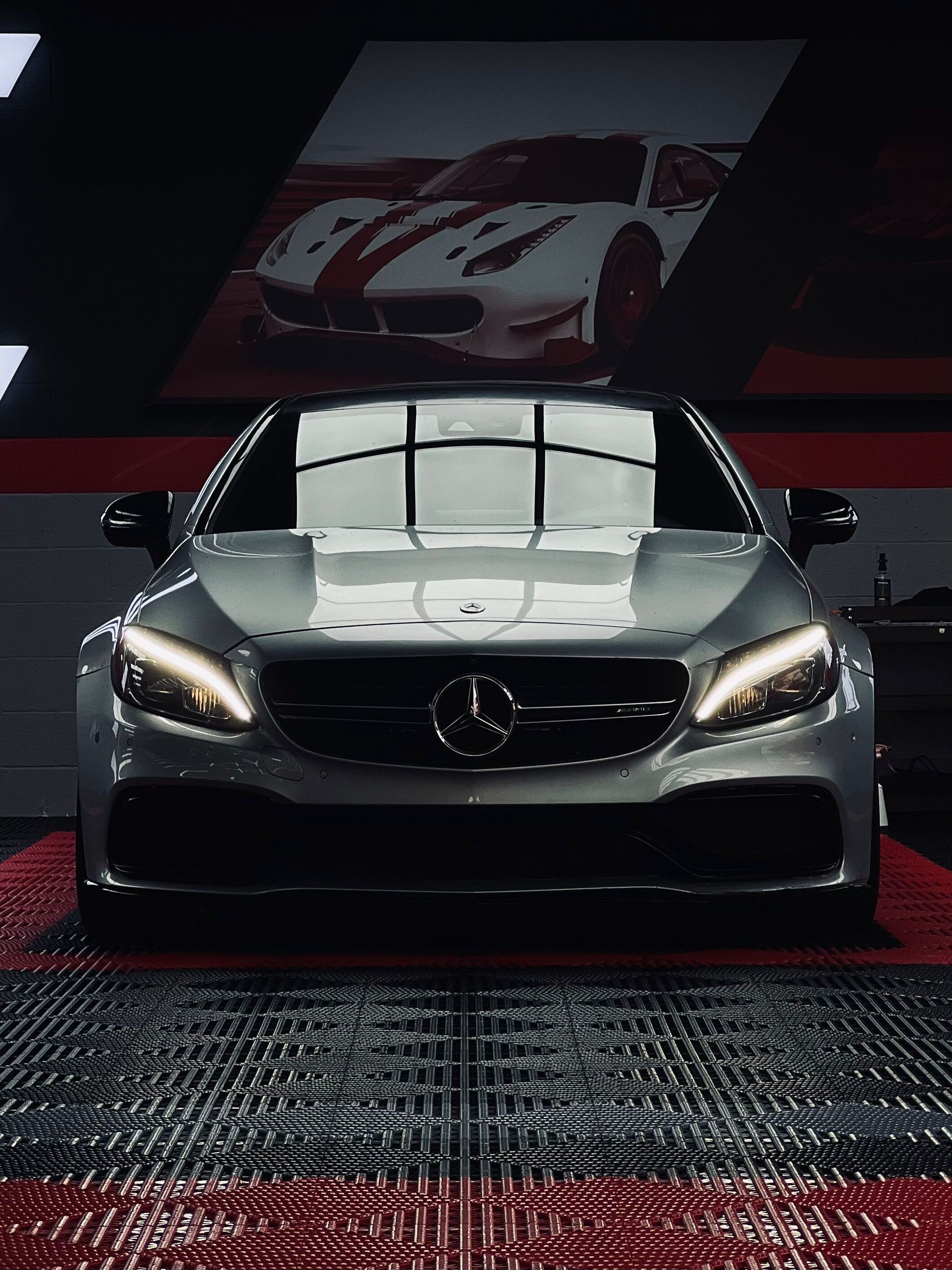 Black cars in a red-lit showroom with digital display walls and arrow graphics