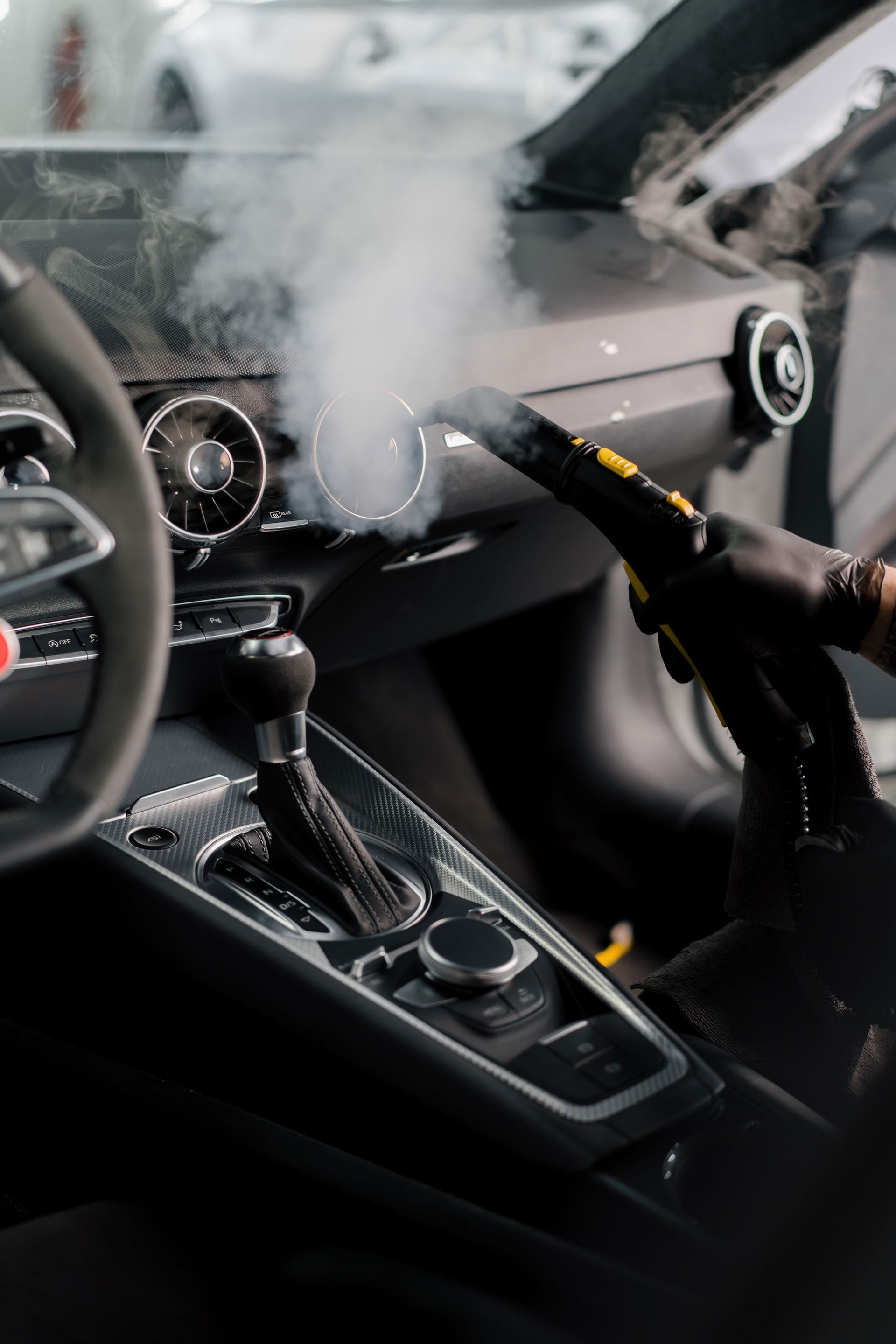 Steam cleaning a car dashboard and center console with a handheld steamer