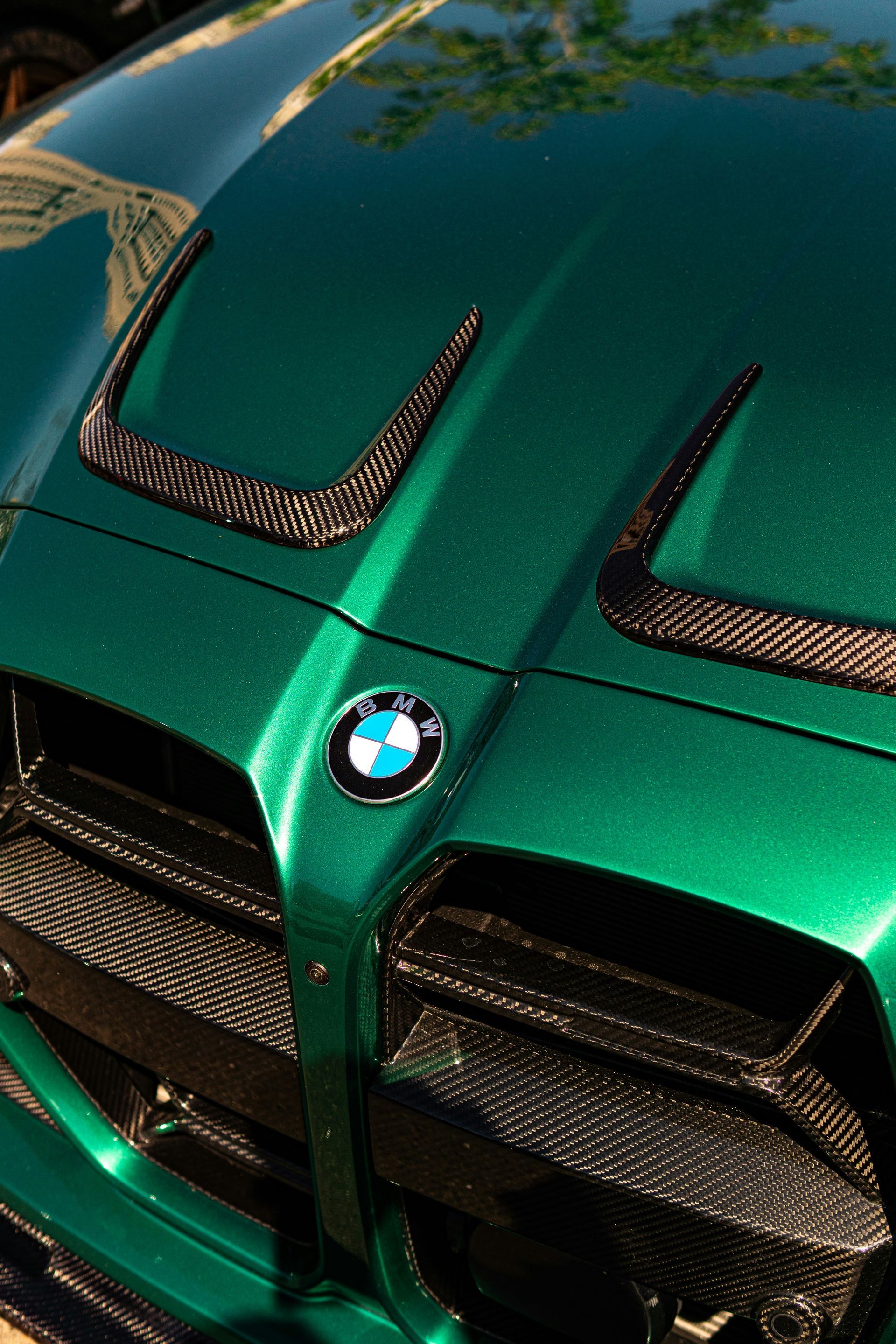 Orange BMW sports car front close-up on a checkered floor, with black grille and headlights.