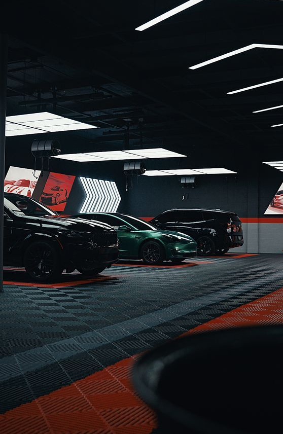 Black cars in a red-lit showroom with digital display walls and arrow graphics