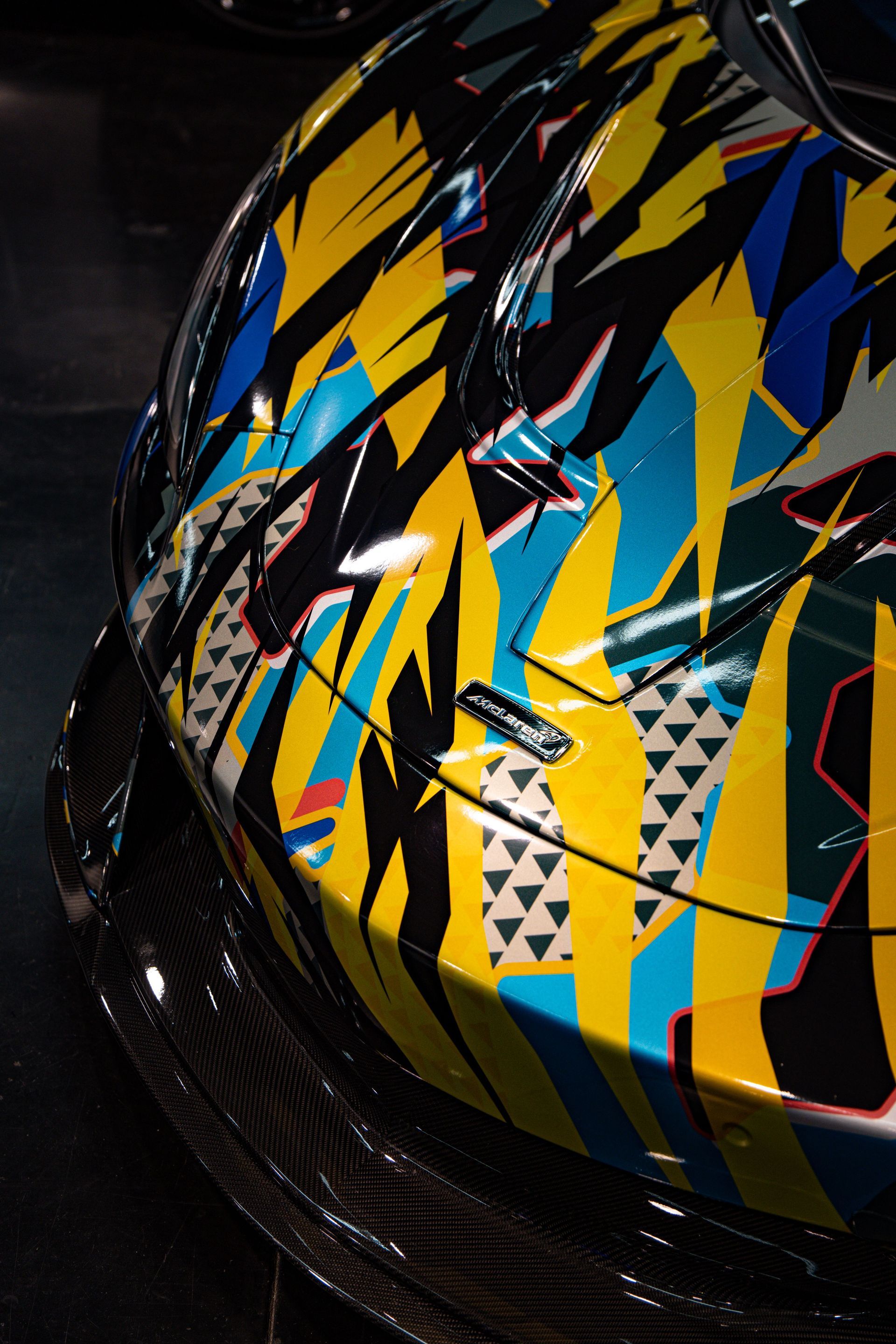 Close-up of a glossy helmet with black, yellow, blue, and red angular patterns