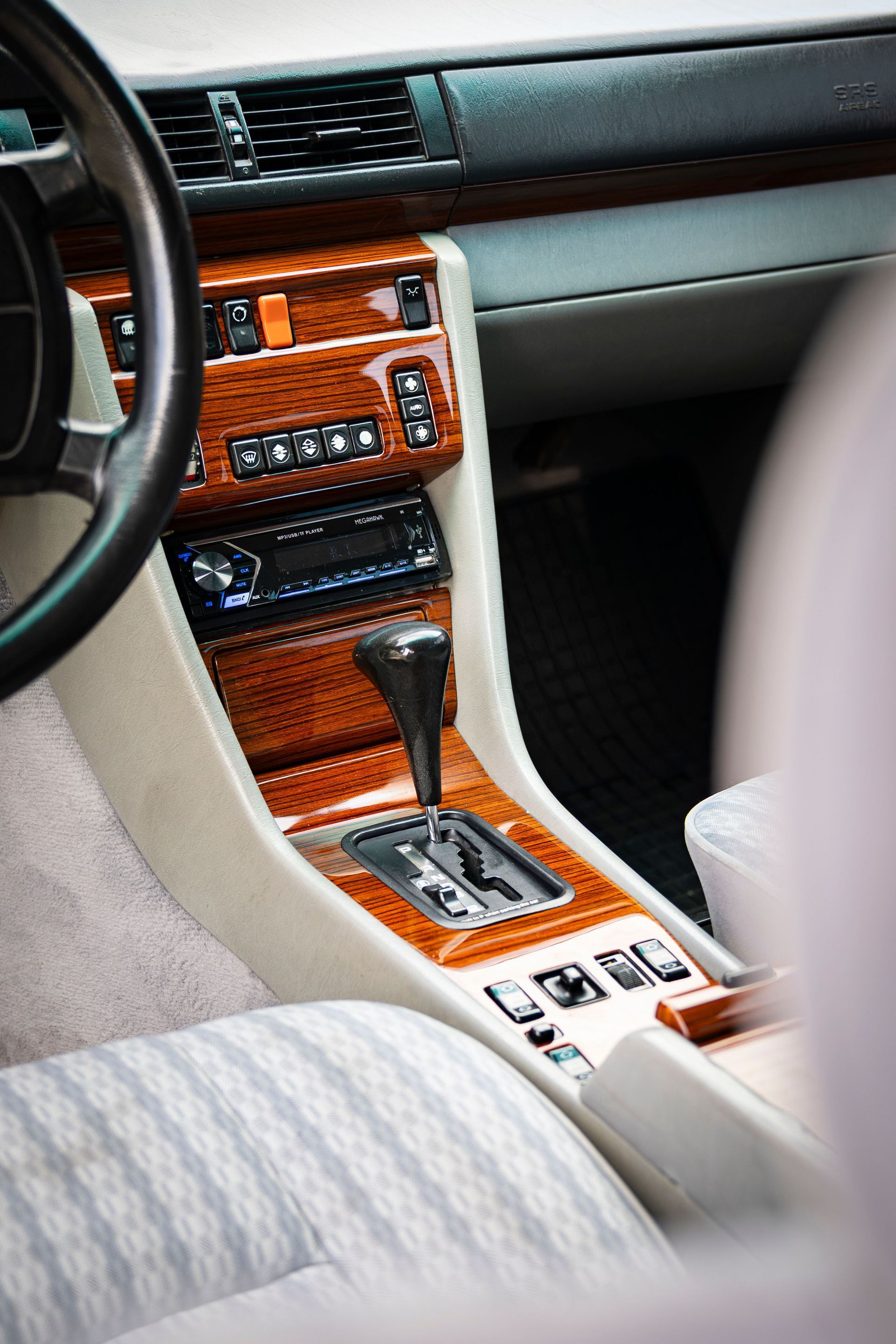Car interior with wood-trimmed center console, gear shift, and beige seats