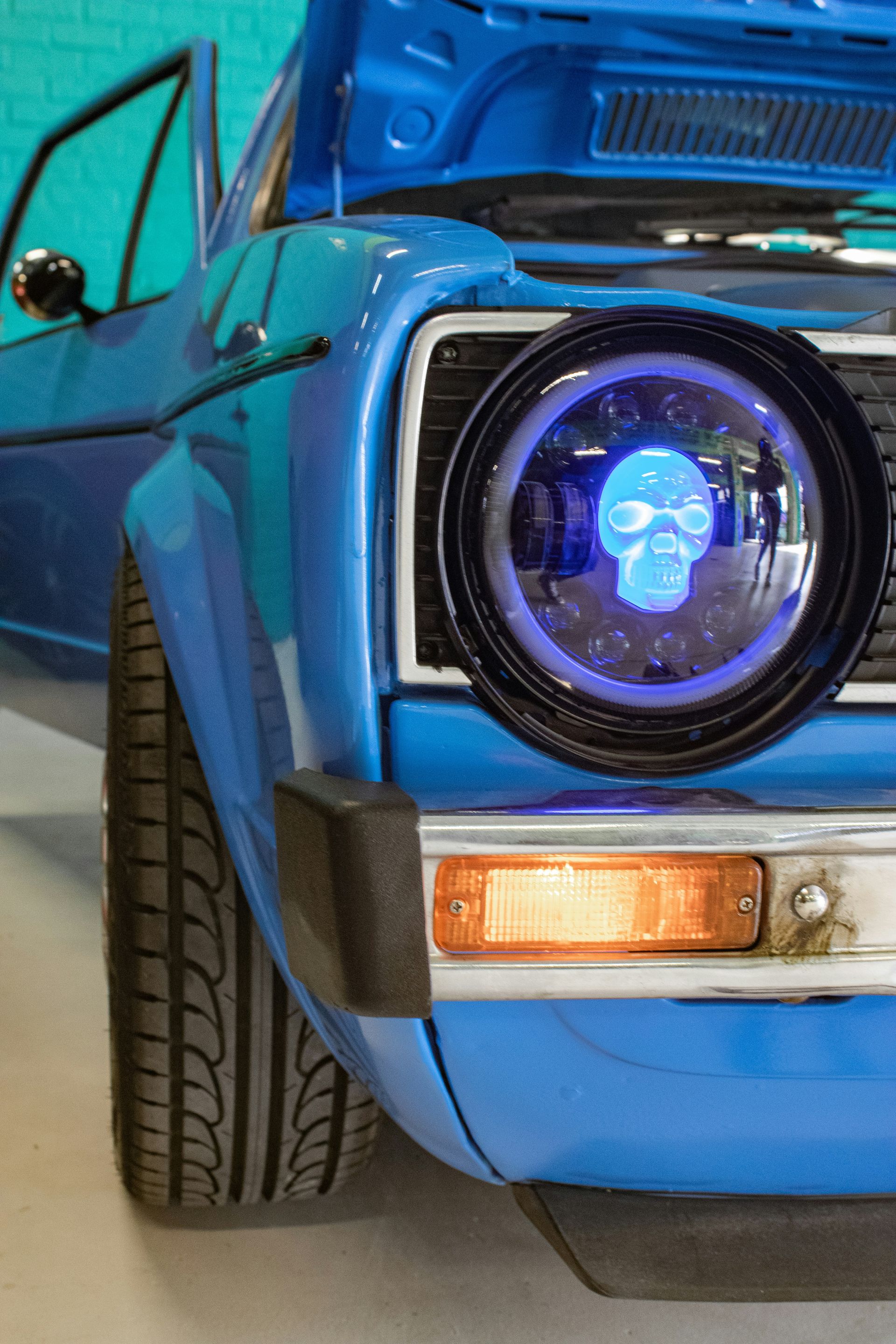 Blue vintage car front end with a custom glowing headlight and open hood