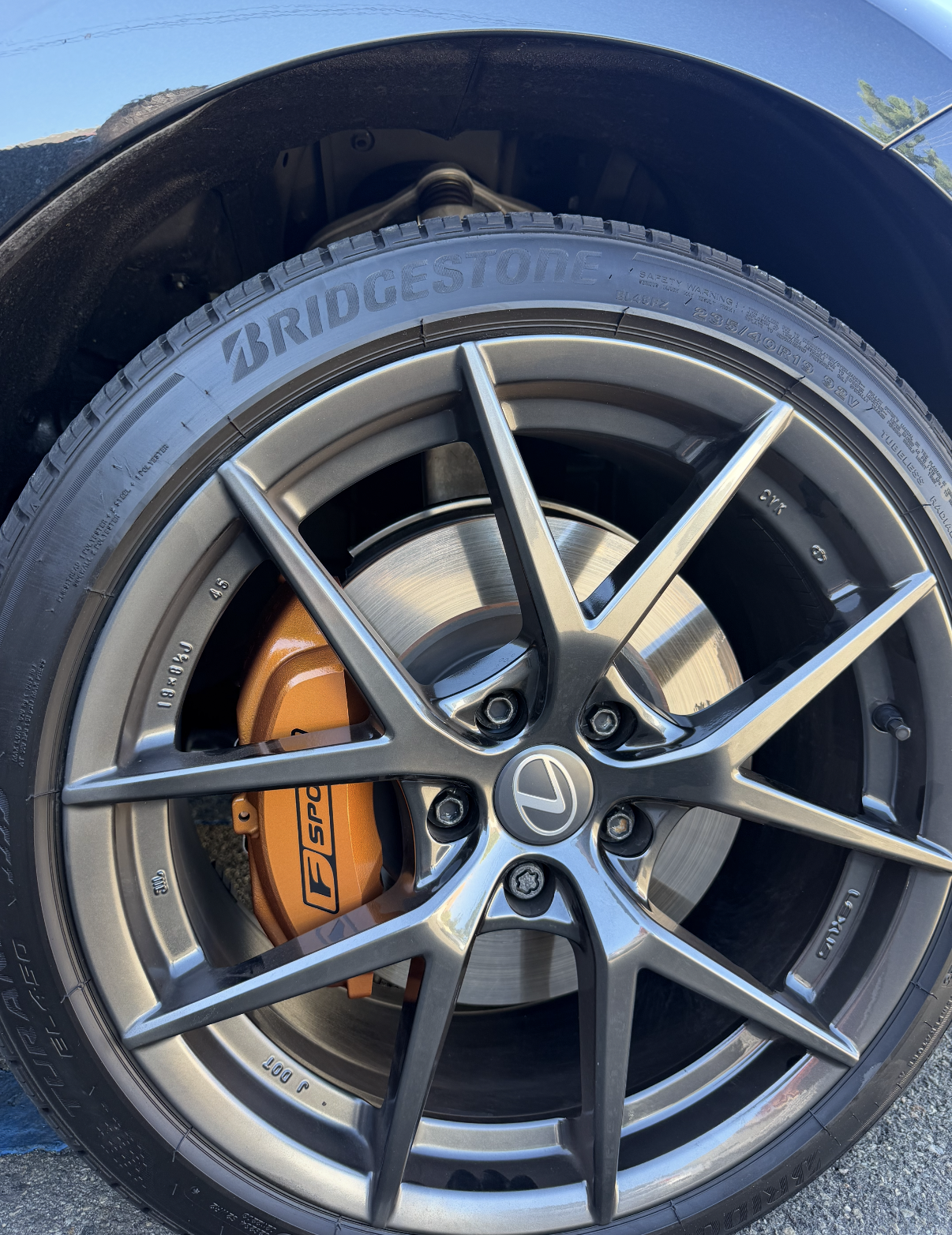 Close-up of a car wheel with a yellow brake caliper and green body panel