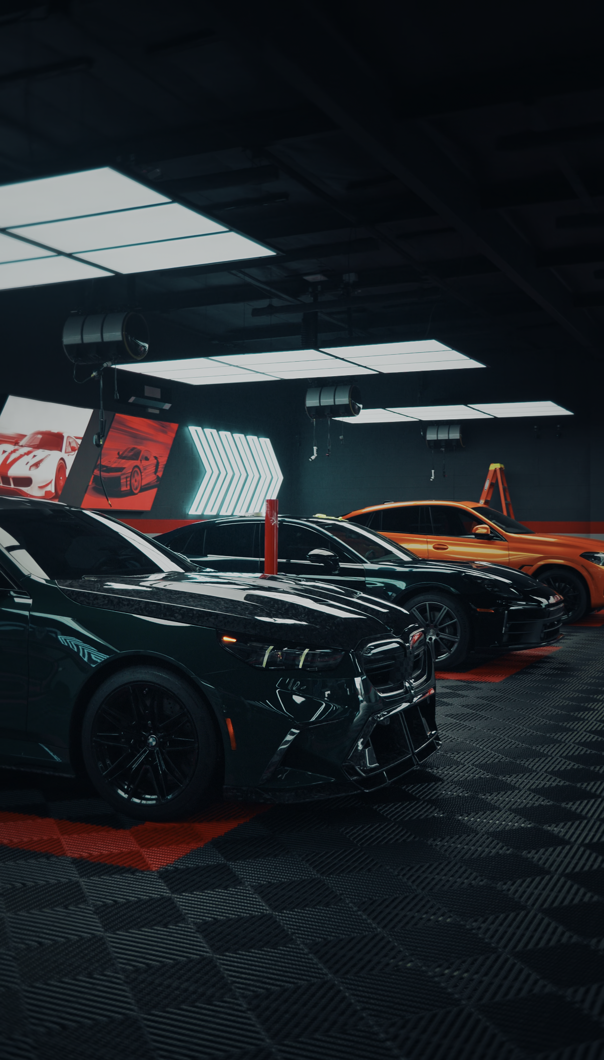 Black cars in a red-lit showroom with digital display walls and arrow graphics