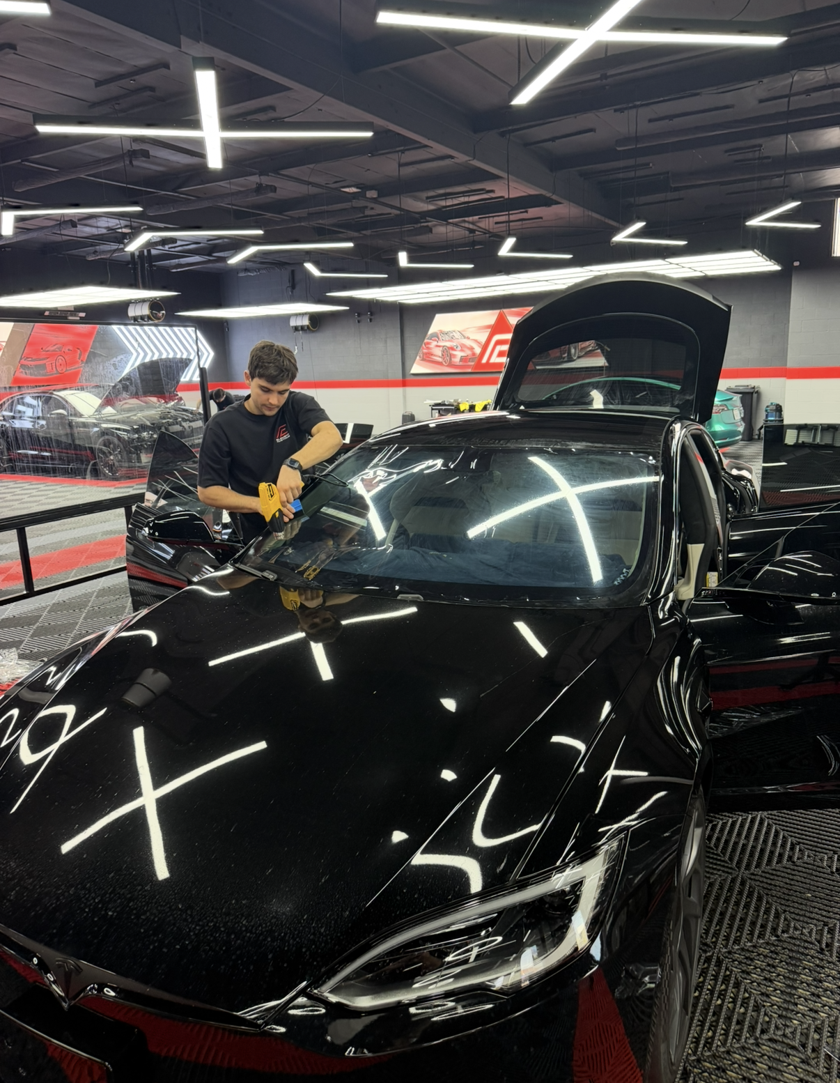 Front view of a silver sports car in a dim showroom with red illuminated displays.