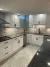 Modern white kitchen with mosaic tile backsplash, dark countertops, and light tile floor