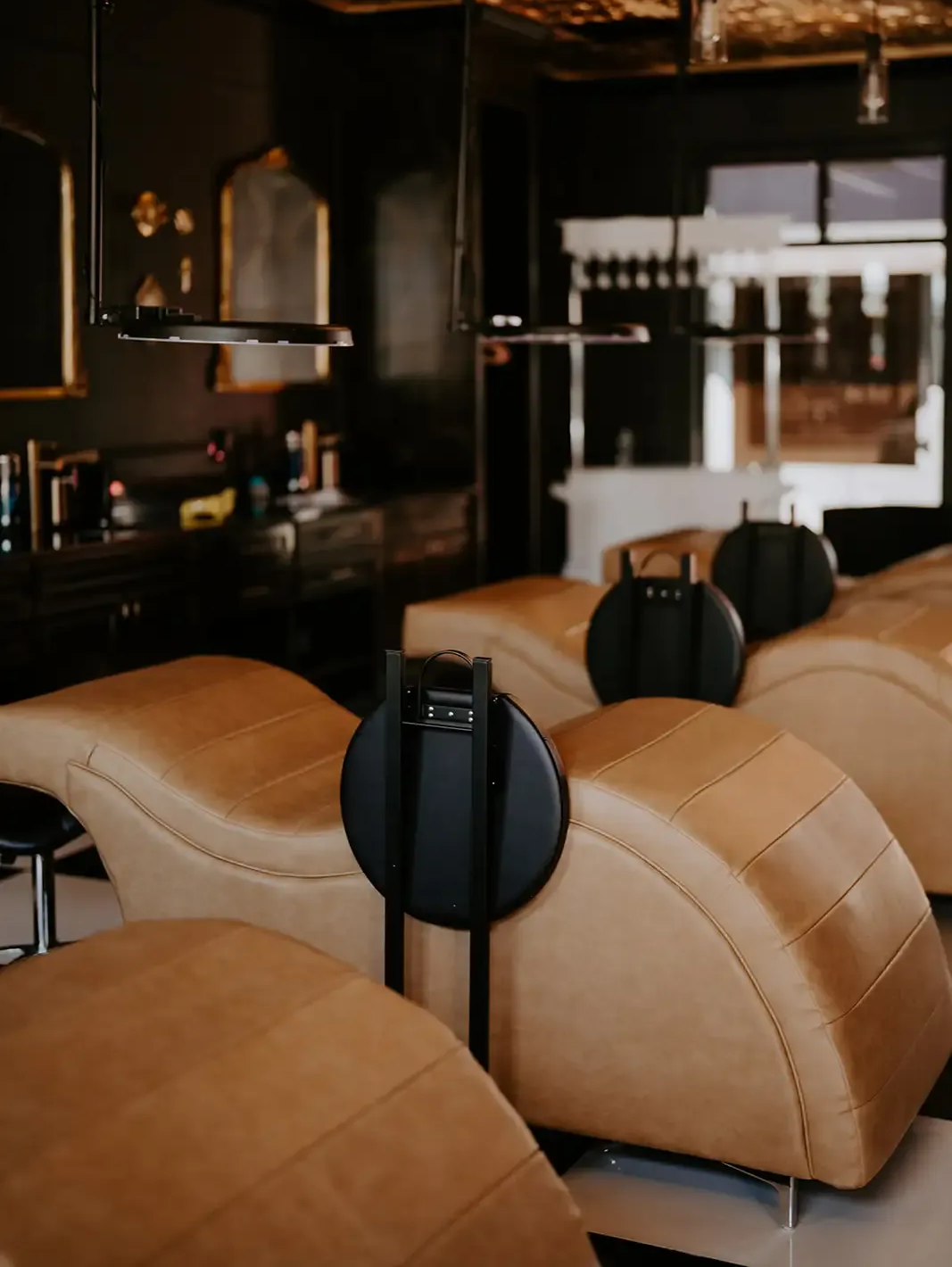 Tan leather lounge chairs in a dim, modern bar or cafe interior