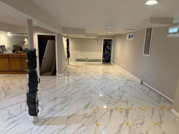 Empty carpeted basement hallway with white walls, windows, and doors under recessed lighting