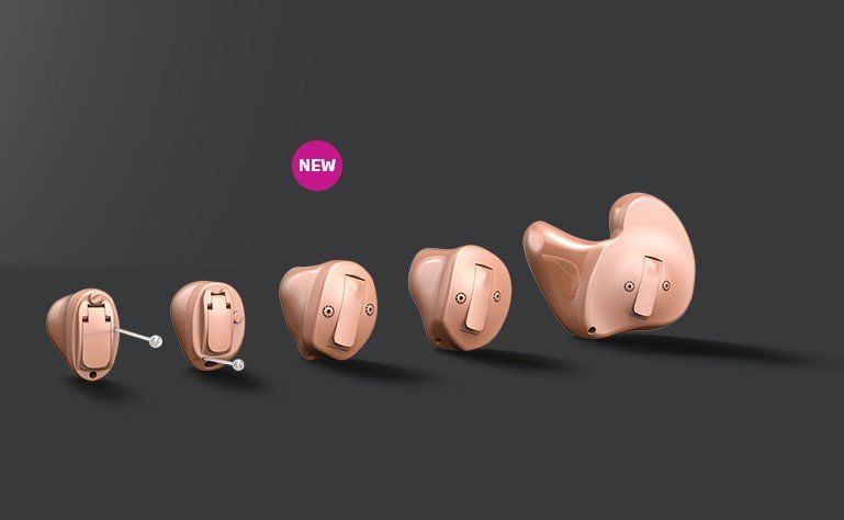 A group of hearing aids are lined up in a row on a black background.